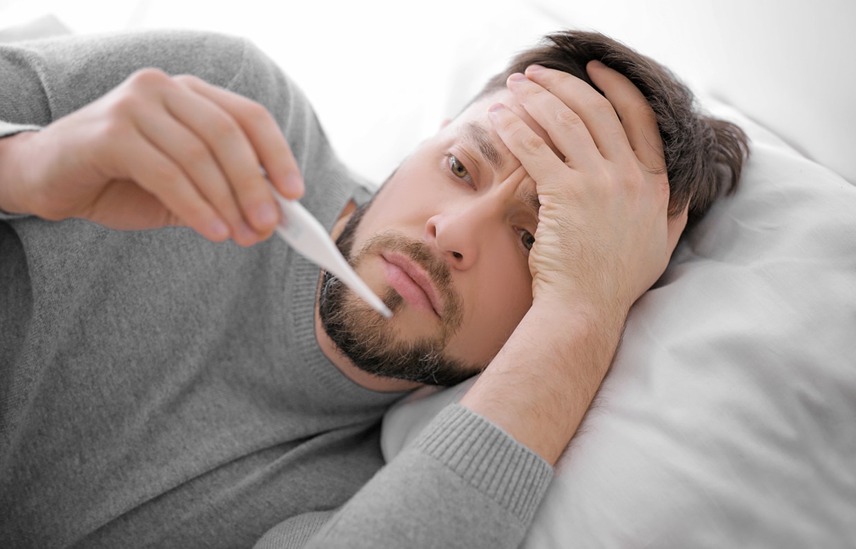 muž v posteli s teploměrem